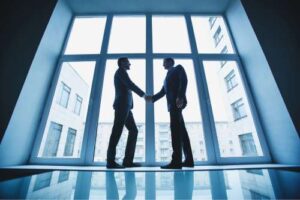 Two businessmen shaking hand in front of a window
