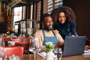 A man and woman looking at a laptop in a small business restaurant